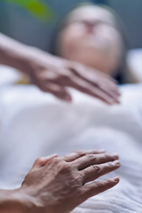 manos-sobre-el-cuerpo- de-paciente-aplicacion-reiki